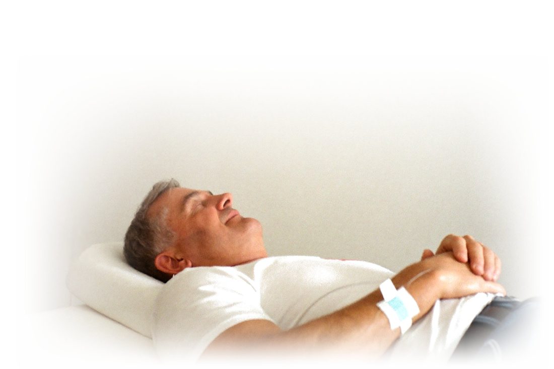 Ein Mann liegt auf einer Behandlungsliege und erhält eine Infusion.